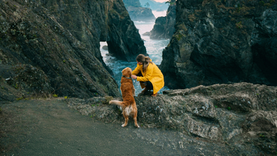 femme portant un imperméable jaune caressant son chien.