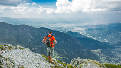 Homme faisant une randonnée dans les montagne et admirant le paysage.