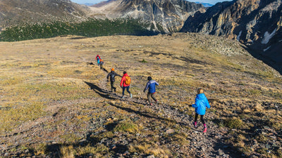 Hommes et femmes de dos faisant une randonnée dans les montagnes